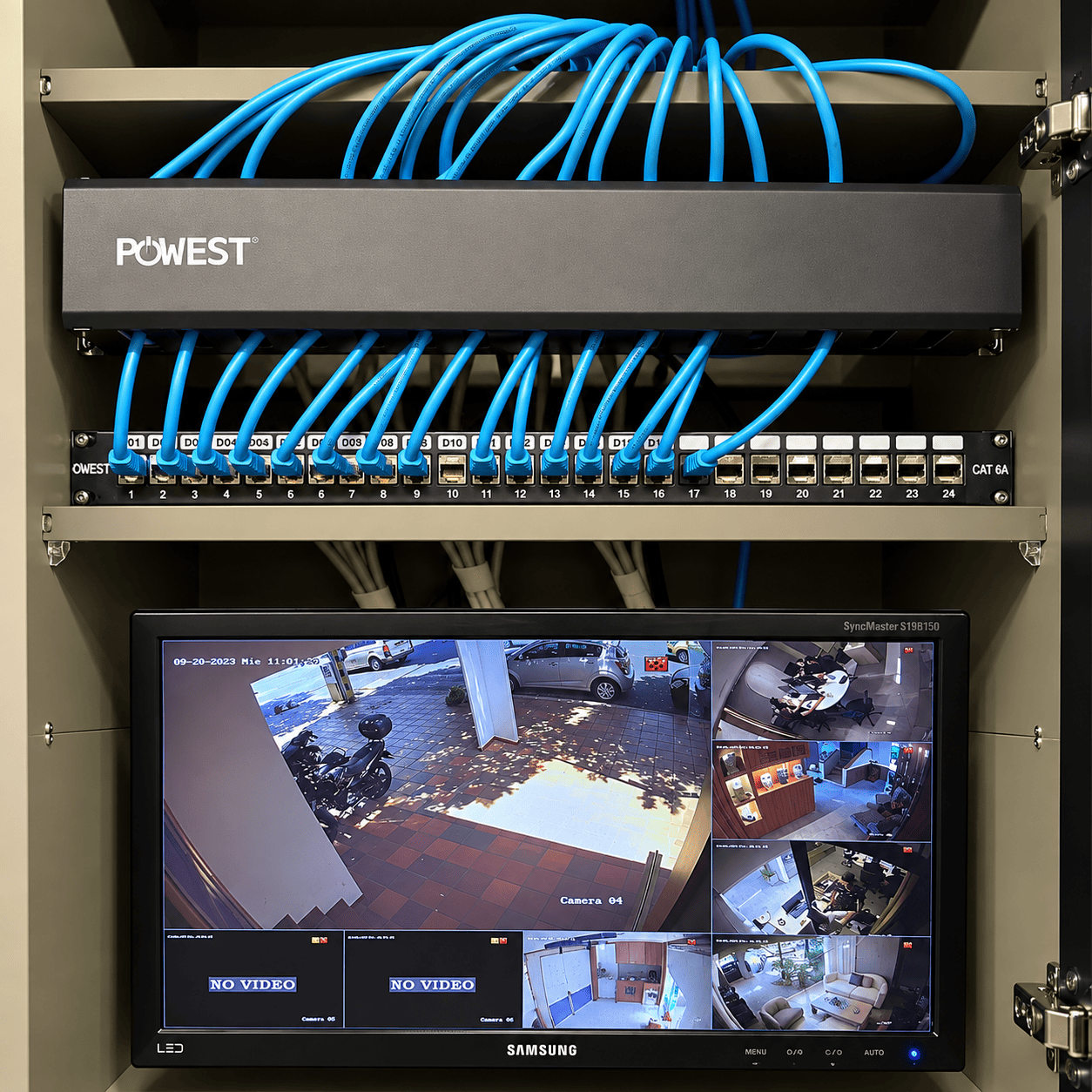 Panel de conexiones con cables de red azules y monitor de videovigilancia en el rack de A5 Studio.