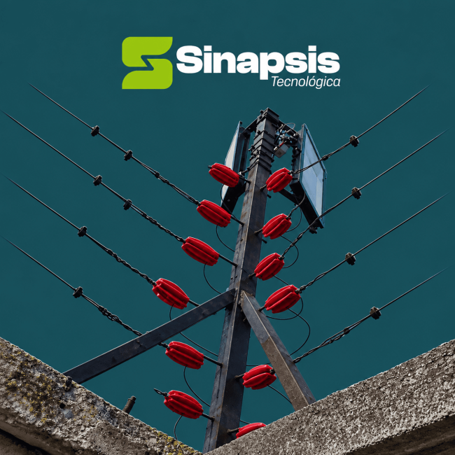 Cerca eléctrica con aisladores rojos sobre un muro, con logotipo de Sinapsis Tecnológica.