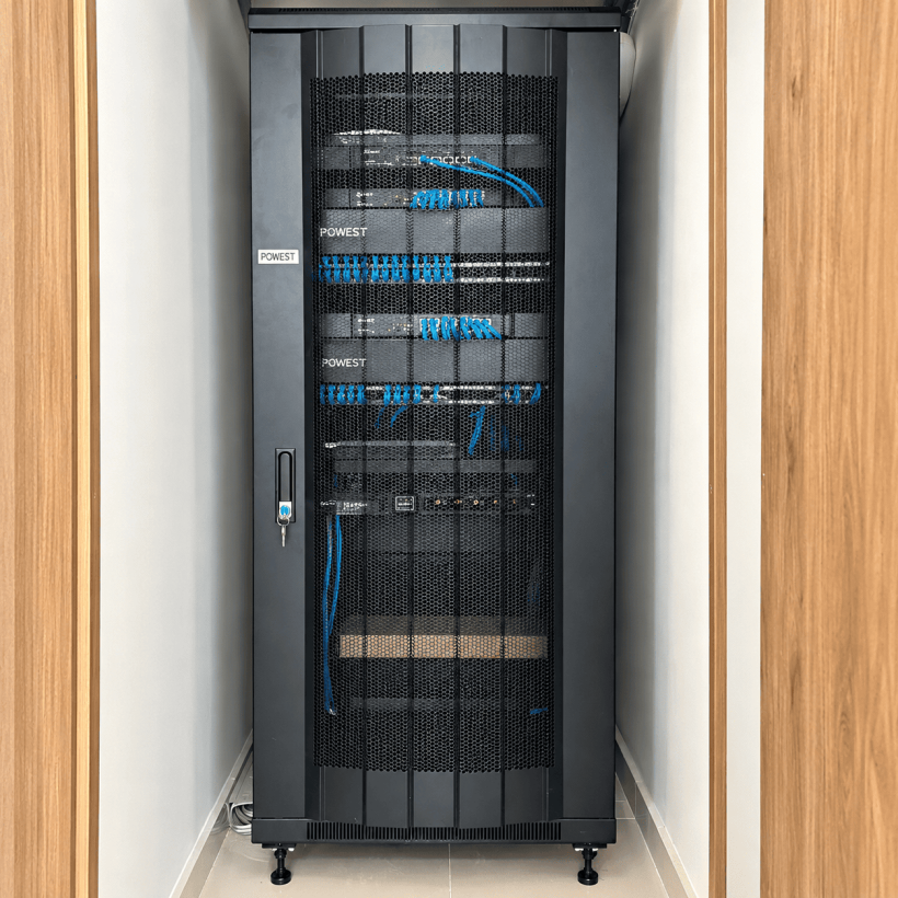 Gabinete de comunicaciones de Carboindustrias con puerta de malla cerrada y cableado de red organizado.