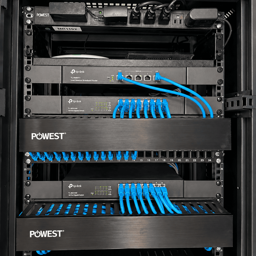 Detalle de switches TP-Link, paneles de conexión y cables de red azules en el rack de Carboindustrias.